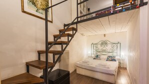 A bedroom with a wooden staircase, a bed with a green metal headboard, and a radiator. - Florence Hideaway by Mmega (Florence)