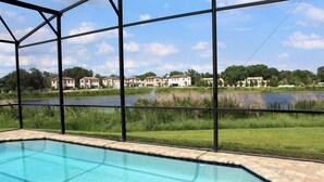 A swimming pool with a view of a lake and residential buildings in the background. - Stunning Lake View Balmoral Estate 4 Bedroom (Haines City)