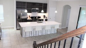A modern kitchen with a central island, stainless steel appliances, and pendant lighting. - Stunning Lake View Balmoral Estate 4 Bedroom (Haines City)
