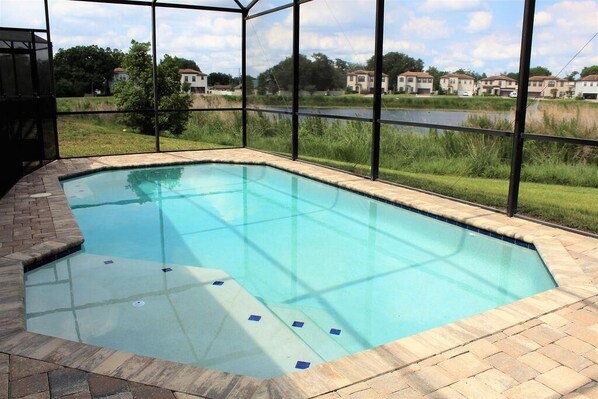 A rectangular swimming pool with a brick border, surrounded by a glass enclosure. - Stunning Lake View Balmoral Estate 4 Bedroom (Haines City)