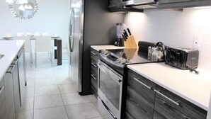 A modern kitchen with stainless steel appliances, a white countertop, and a knife block. - Stunning Lake View Balmoral Estate 4 Bedroom (Haines City)