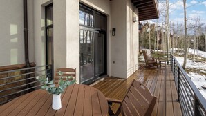 A wooden deck with a table and chairs, a potted plant, and a sliding glass door leading to an indoor area. - Excellent location in Mountain Village core, spacious and cozy condo (Mountain Village)