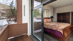 A bedroom with a bed, a nightstand, a window, and a door leading to a balcony. - Excellent location in Mountain Village core, spacious and cozy condo (Mountain Village)