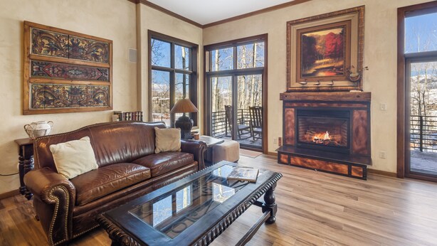 A spacious living room with a fireplace, leather sofa, and large windows. - Excellent location in Mountain Village core, spacious and cozy condo (Mountain Village)