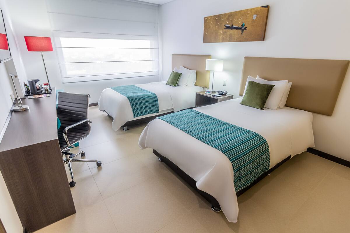 Une chambre d’hôtel avec deux lits, un bureau et une chaise.