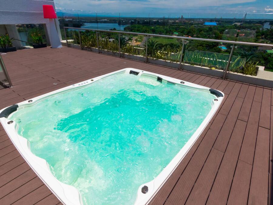 Un jacuzzi en una terraza de madera con vistas a un paisaje urbano.
