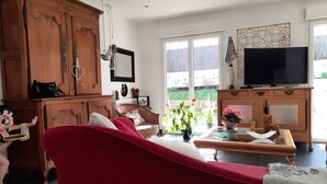 A spacious living room with a red sofa, wooden cabinets, a television, and a view of the outdoors.