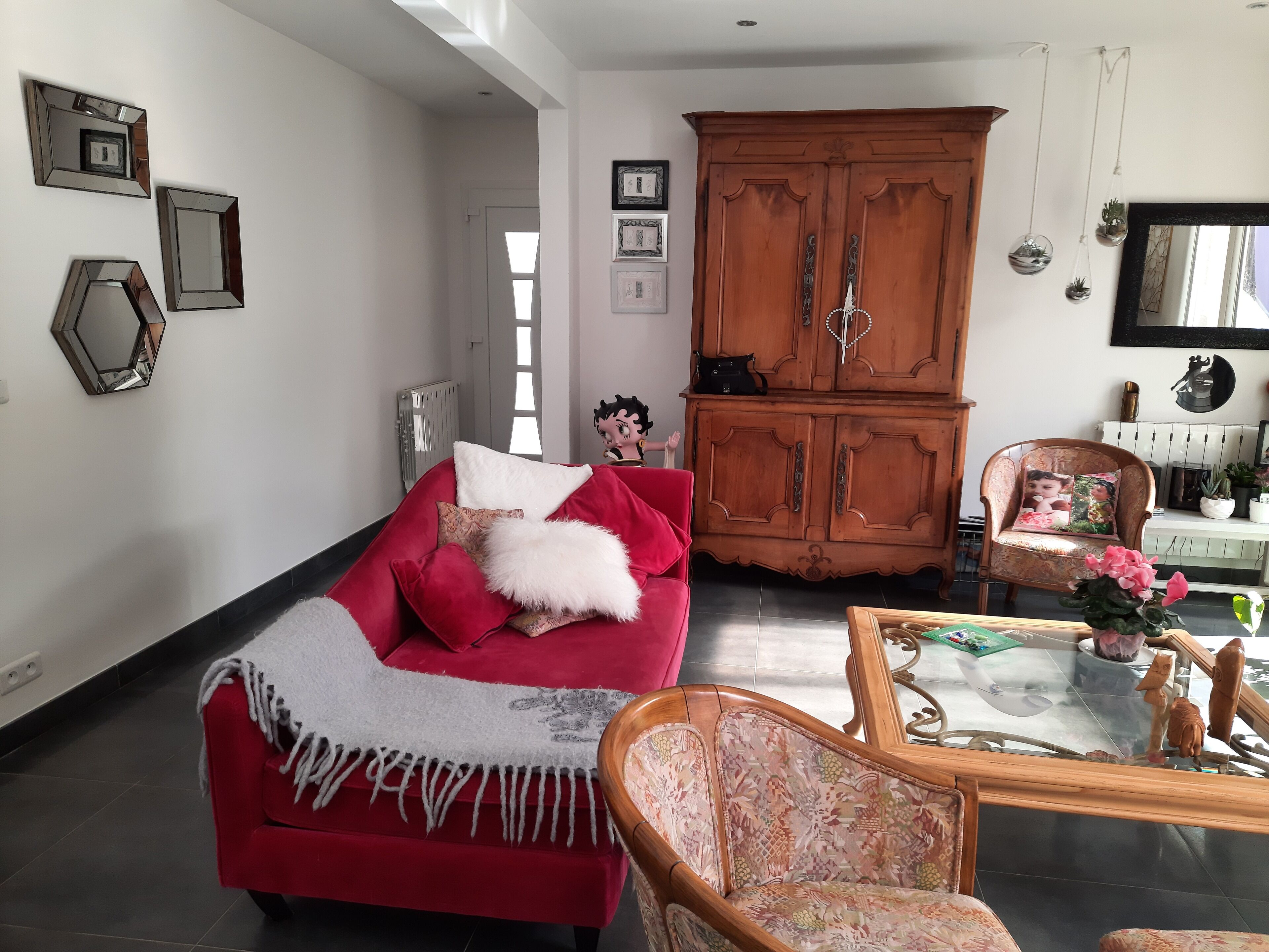Un salon avec un canapé rouge, un meuble en bois et un fauteuil à motifs.