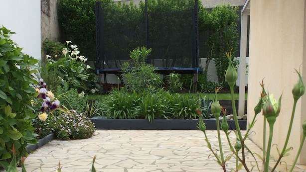 A stone-tiled patio with green plants and a black screen in the background.