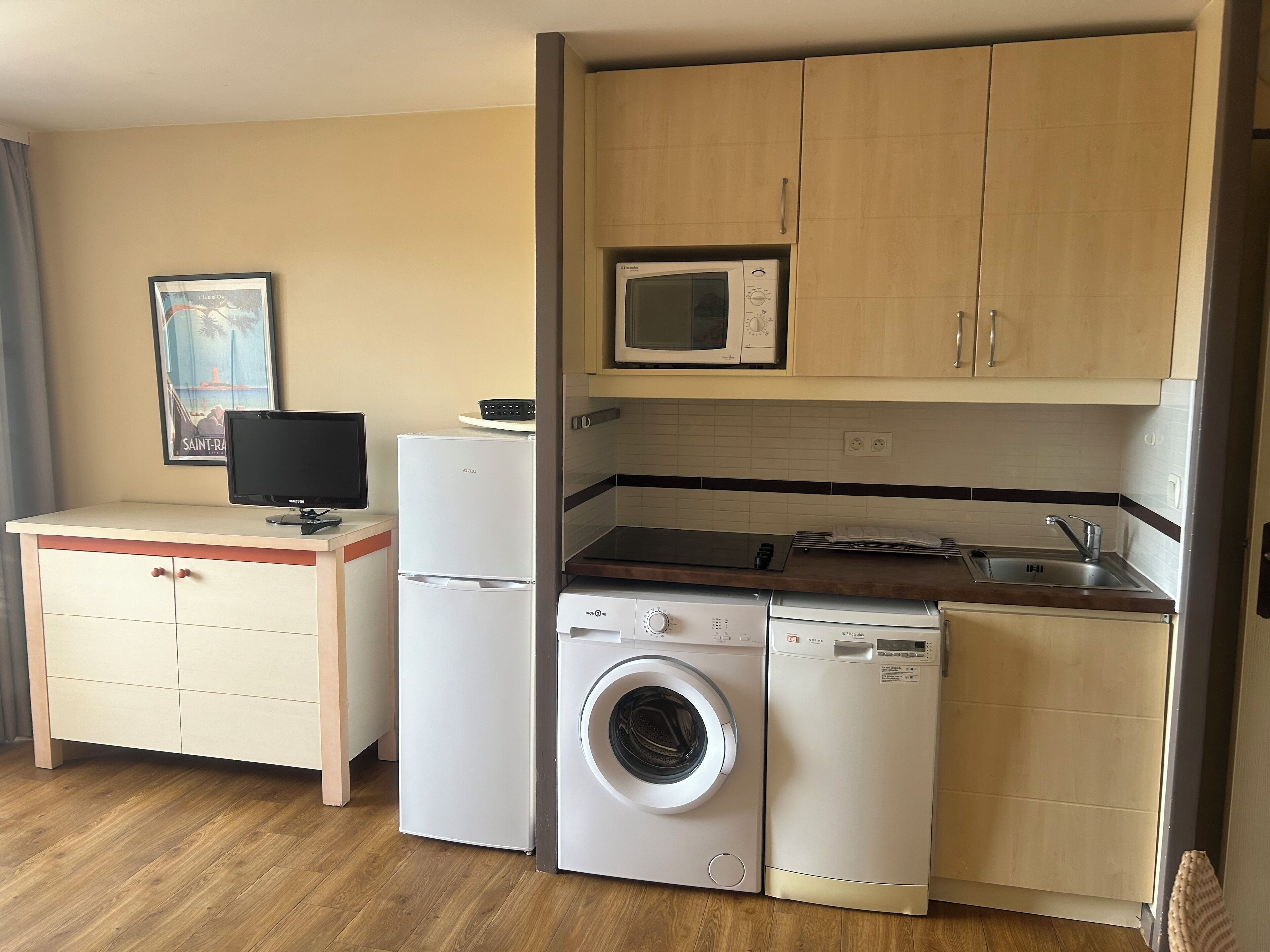 A compact kitchen with a microwave, a washing machine, and a sink.