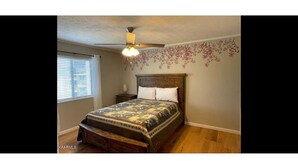 A bedroom with a wooden bed, a ceiling fan, and a window with blinds. - Mountain View 2BR Condo - No Cleaning Fee - Close to Downtown (Gatlinburg)