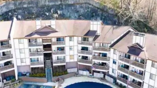 A multi-story hotel with balconies, a swimming pool, and a landscaped area. - Mountain View 2BR Condo - No Cleaning Fee - Close to Downtown (Gatlinburg)