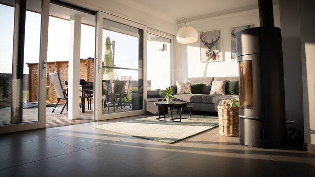 A modern living room with a sofa, coffee table, and a large window. - Modern vacation home with terrace and outdoor sauna (Schermbeck)