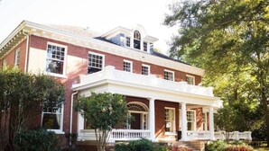 A large brick house with a covered porch and a small garden.