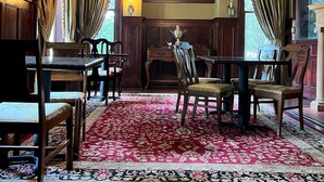 A formal dining room with a chandelier, wooden furniture, and a red patterned rug.