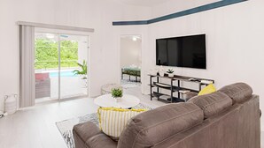 Una sala de estar moderna con un televisor grande, un sofá y una mesa de centro.