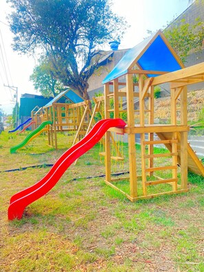 A playground with multiple slides and wooden playhouses.