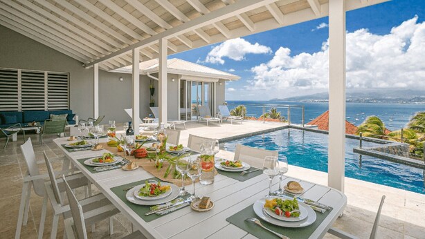 A dining area with a view of the sea and a pool. - Tangarane offers two luxury villas with private pools and exceptional views over (LES TROIS ILETS)