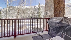 A balcony with a stone wall, a covered grill, and a view of snow-covered mountains. - Two Hot Tubs, Amazing Views, Right next to the Lift, Entertainment area. CS110 (Copper Mountain)