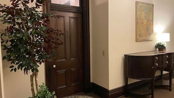 A wooden door with a small window, a dark wooden desk with drawers, a potted plant, and a patterned rug.