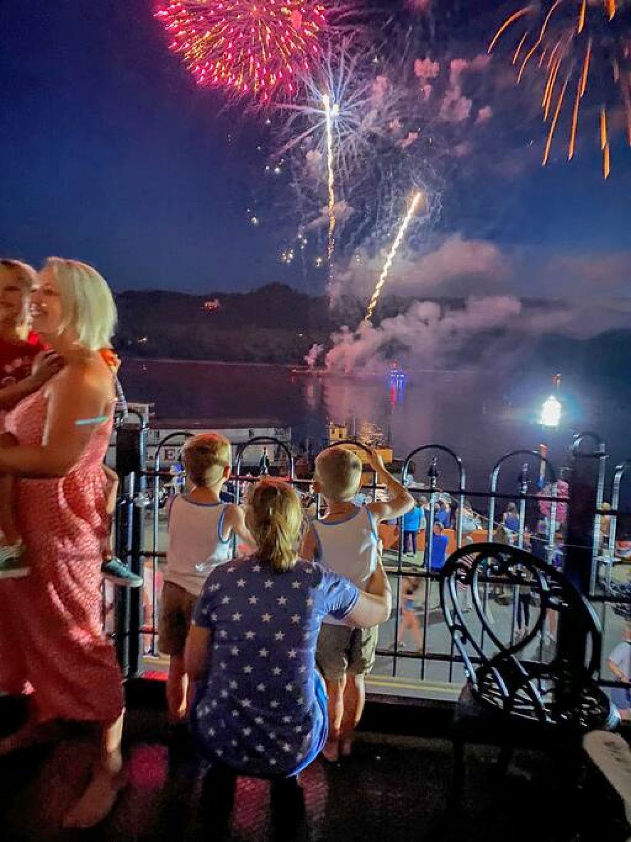 A nighttime view of a waterfront with fireworks display.