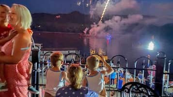 A nighttime view of a waterfront with fireworks display.