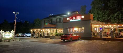 Ein Gebäude mit der Aufschrift „EL BARRIL“ bei Nacht, mit einem Parkplatz und einem roten Auto davor.