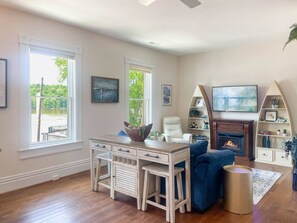 A living room with a fireplace, a desk, and a blue sofa.