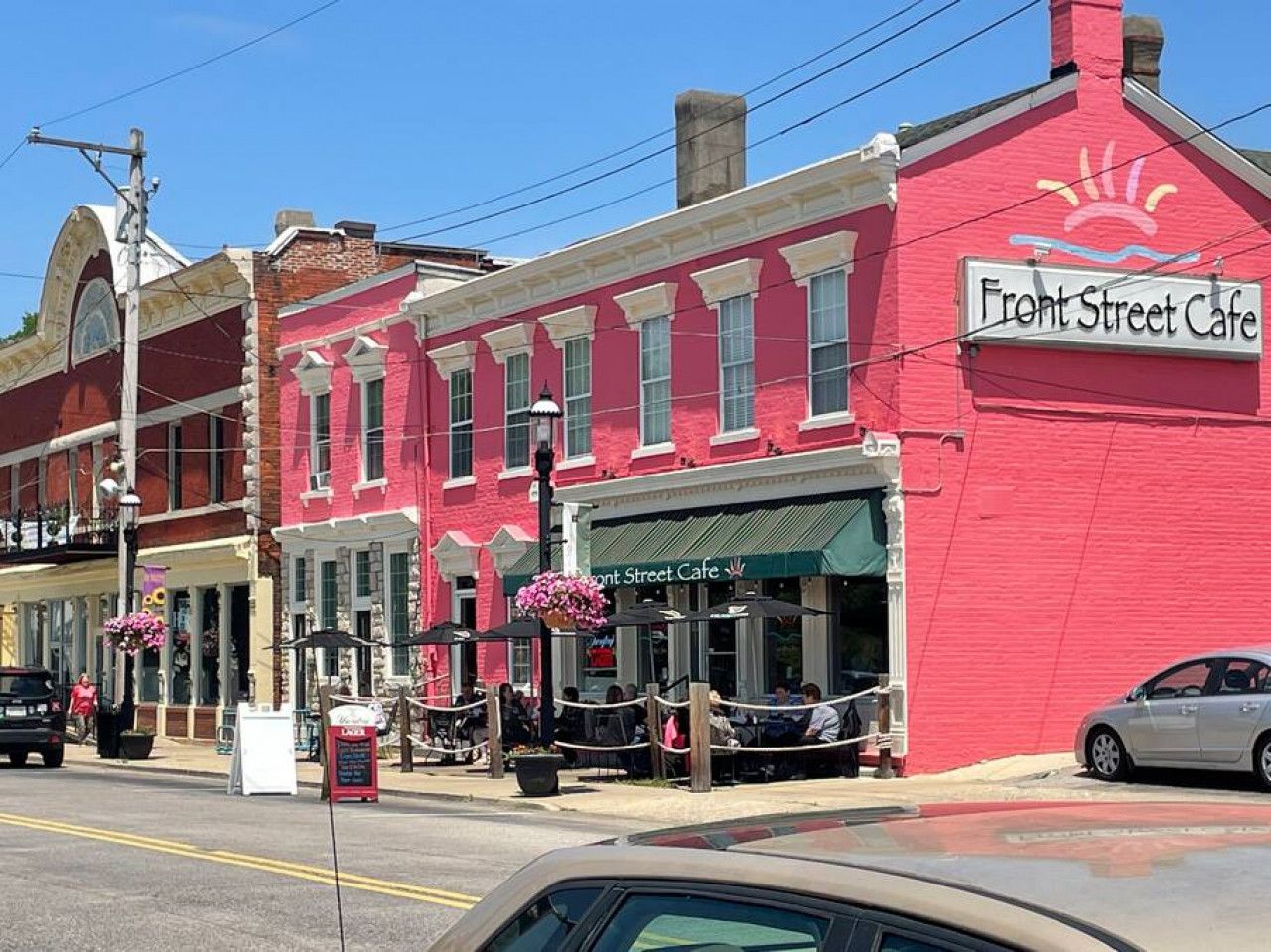 A street view with a red building labeled 'Front Street Cafe' and a visible storefront with outdoor seating.