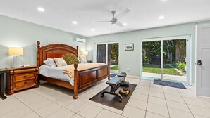 A bedroom with a wooden bed, a desk, a chair, and a small exercise mat with dumbbells.