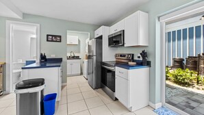 A modern kitchen with white cabinets, stainless steel appliances, and a blue countertop.
