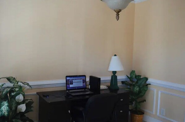 A room with a desk, a laptop, a lamp, and two potted plants. - Blue SeaShell (North Myrtle Beach)