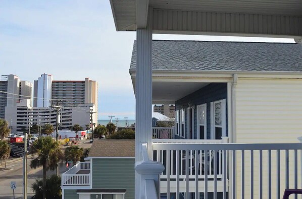 A coastal building with a balcony, adjacent to a street with palm trees and a view of high-rise buildings. - Blue SeaShell (North Myrtle Beach)