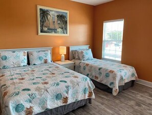 A room with two beds, a painting of sailboats, and a window with blinds. - Blue SeaShell (North Myrtle Beach)