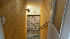 Una escalera de madera con una pared blanca y una estantería en la parte superior.