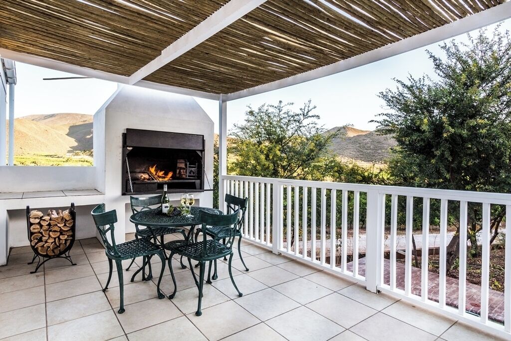 A covered patio with a built-in grill, outdoor seating, and a view of the landscape.