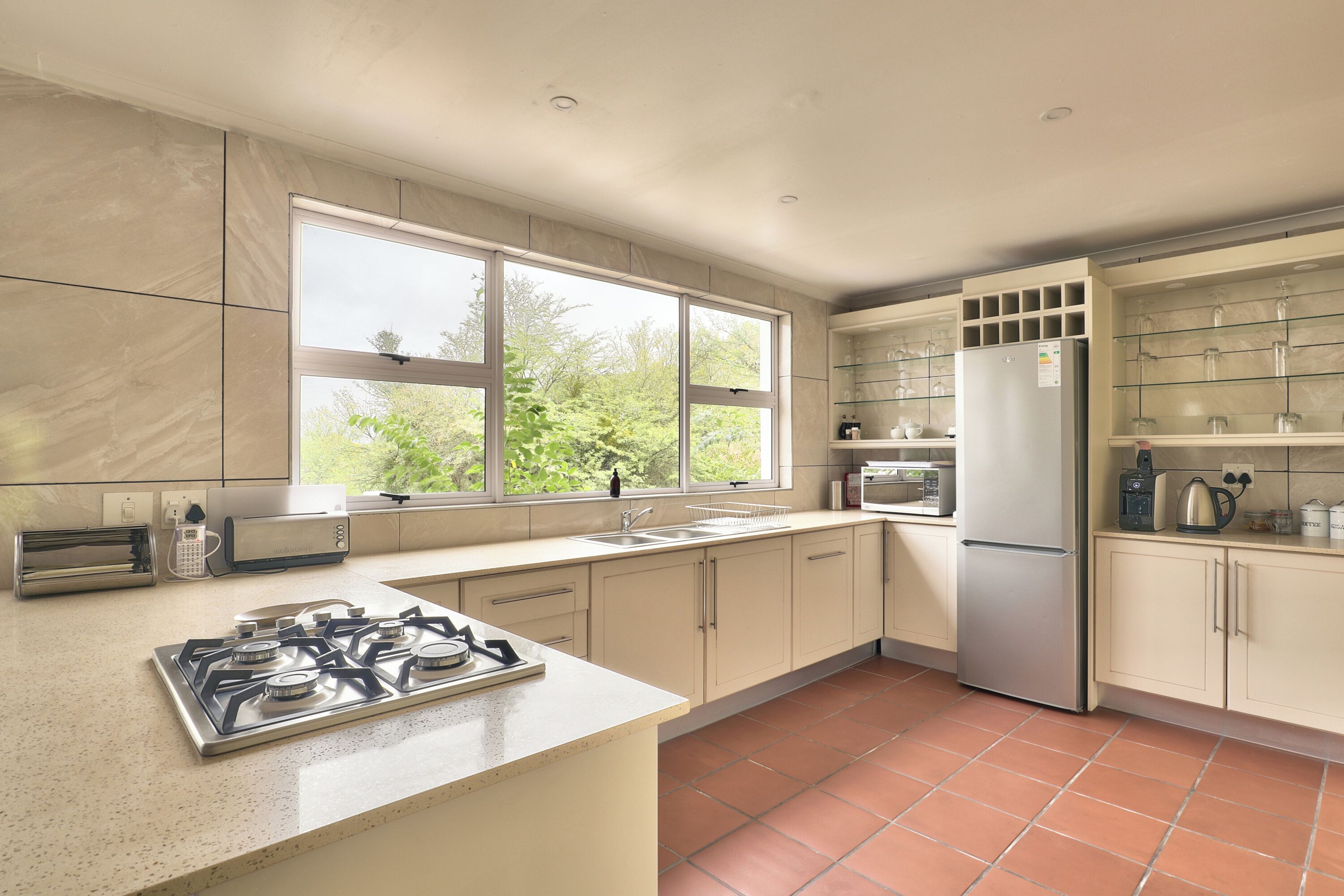 A modern kitchen with a gas stove, a refrigerator, and a window providing natural light.