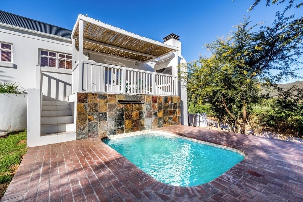 Uma casa moderna com piscina, varanda e muro de pedra.