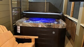 Un jacuzzi con banca de madera, ventana y televisor.
