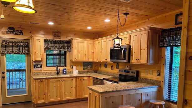 Cocina tipo cabaña de madera con encimeras de granito, microondas integrado y una isla grande con taburetes.