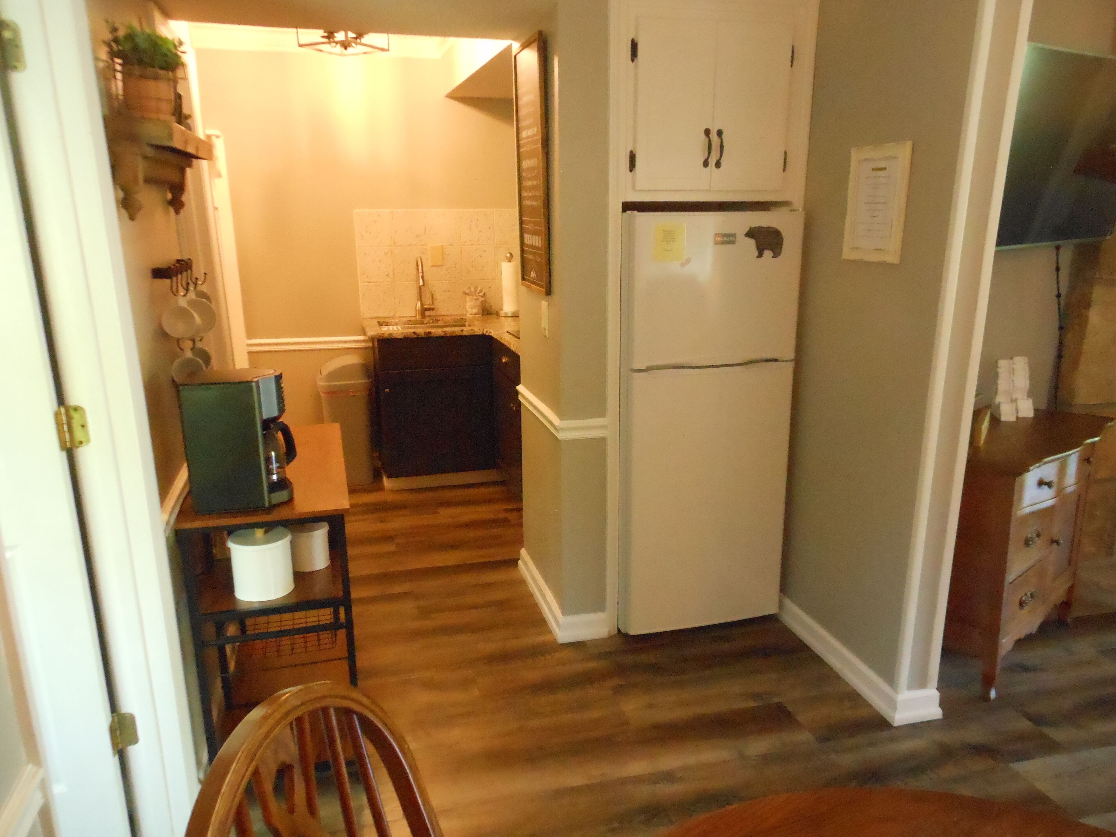 A compact kitchen with a refrigerator, sink, and wooden flooring.