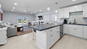 A modern kitchen with white cabinets, a central island, and pendant lighting. - Heated Pool Home steps to the beach (Fort Myers Beach)