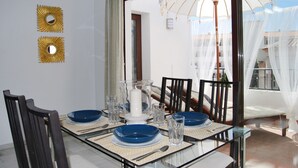 A dining area with a glass table, blue and white plates, and gold decorative mirrors. - Ap140 Alcazaba 2D (Nerja)