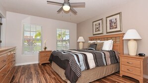 A bedroom with a bed, two bedside tables, a ceiling fan, and two windows with blinds. - Terrific Value 4 Bed Pool Game Spa Home Sandy Ridge (Davenport)
