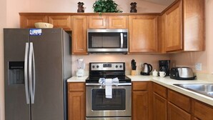 A kitchen with wooden cabinets, a stainless steel refrigerator, a microwave, an oven, and a sink. - Terrific Value 4 Bed Pool Game Spa Home Sandy Ridge (Davenport)