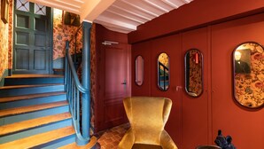A staircase with blue steps and a red door, a gold armchair, and a small statue. - Passocean 2 - Elegant Suite in the Heart of Honfleur - Kingsize (Honfleur)