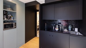 A modern kitchen with built-in appliances, a black backsplash, and a wooden floor. - Passocean 2 - Elegant Suite in the Heart of Honfleur - Kingsize (Honfleur)