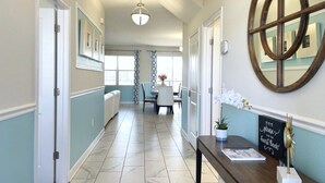 Un pasillo de hotel con una recepción, un espejo y un área de comedor al fondo.