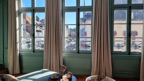 Una habitación con un ventanal grande, una mesa con tetera y tazas, y una silla.
