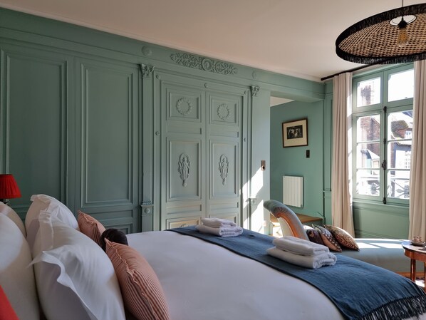 A room with a large bed, a red lamp, and a window with curtains.